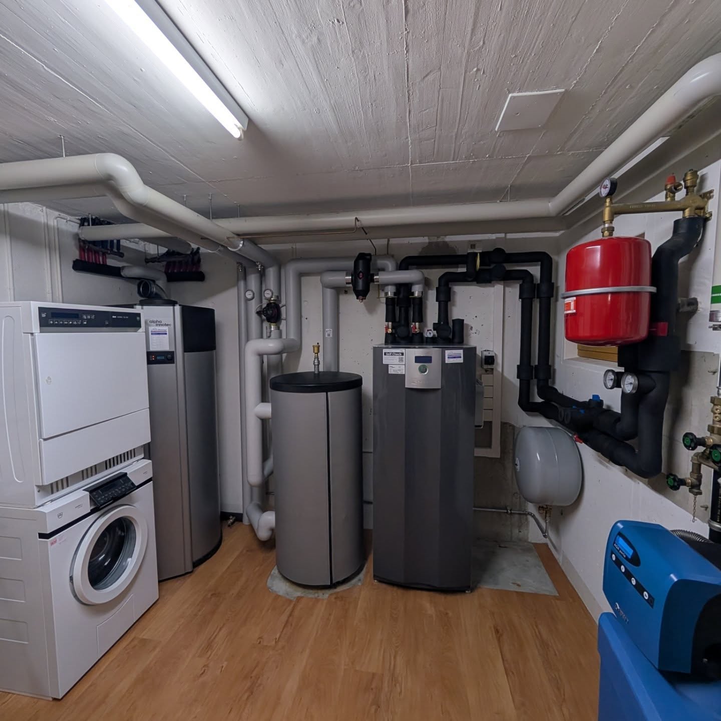 Technikraum mit Waschmaschine, Wärmepumpe und rotem Ausdehnungsgefäss